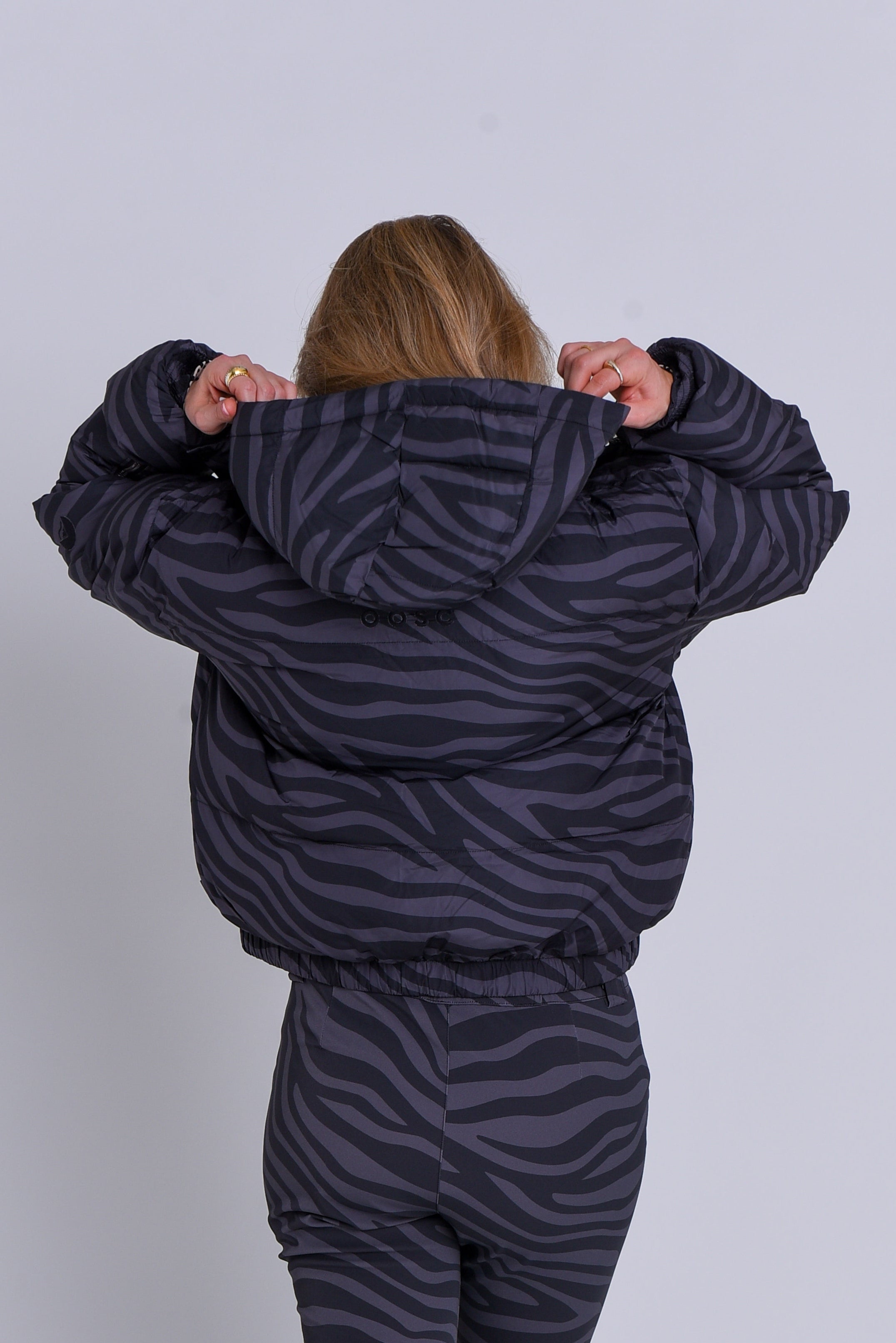 Person wearing a zebra-striped puffer suit against a white background